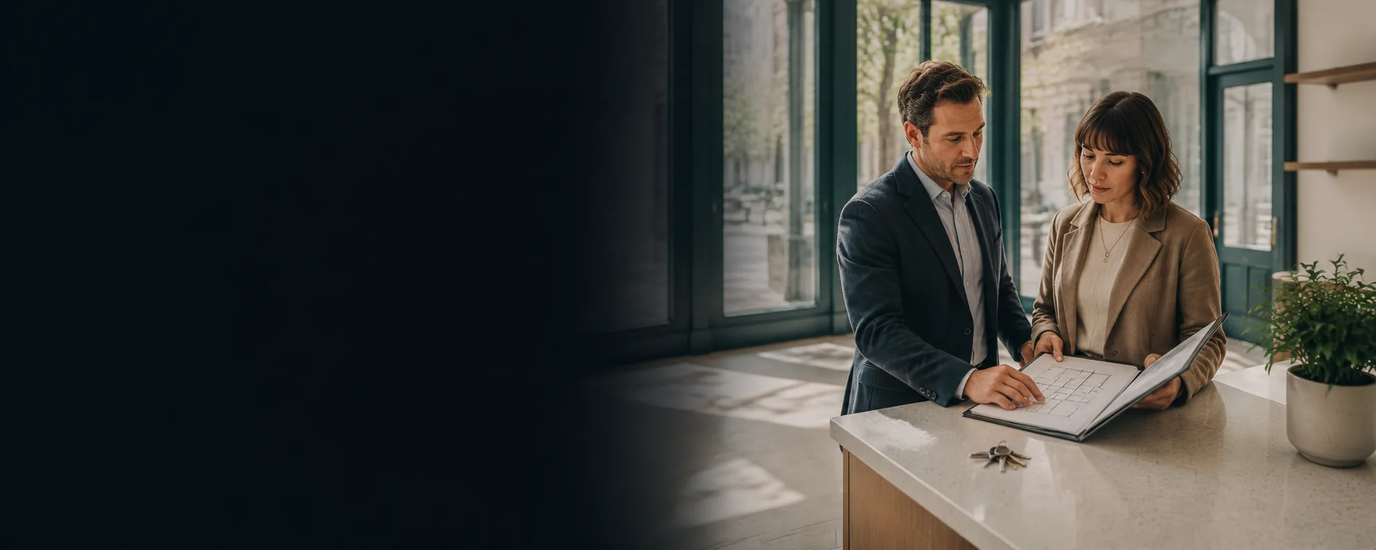 Two people reviewing a lease plan and keys on a counter in a bright entrance hall