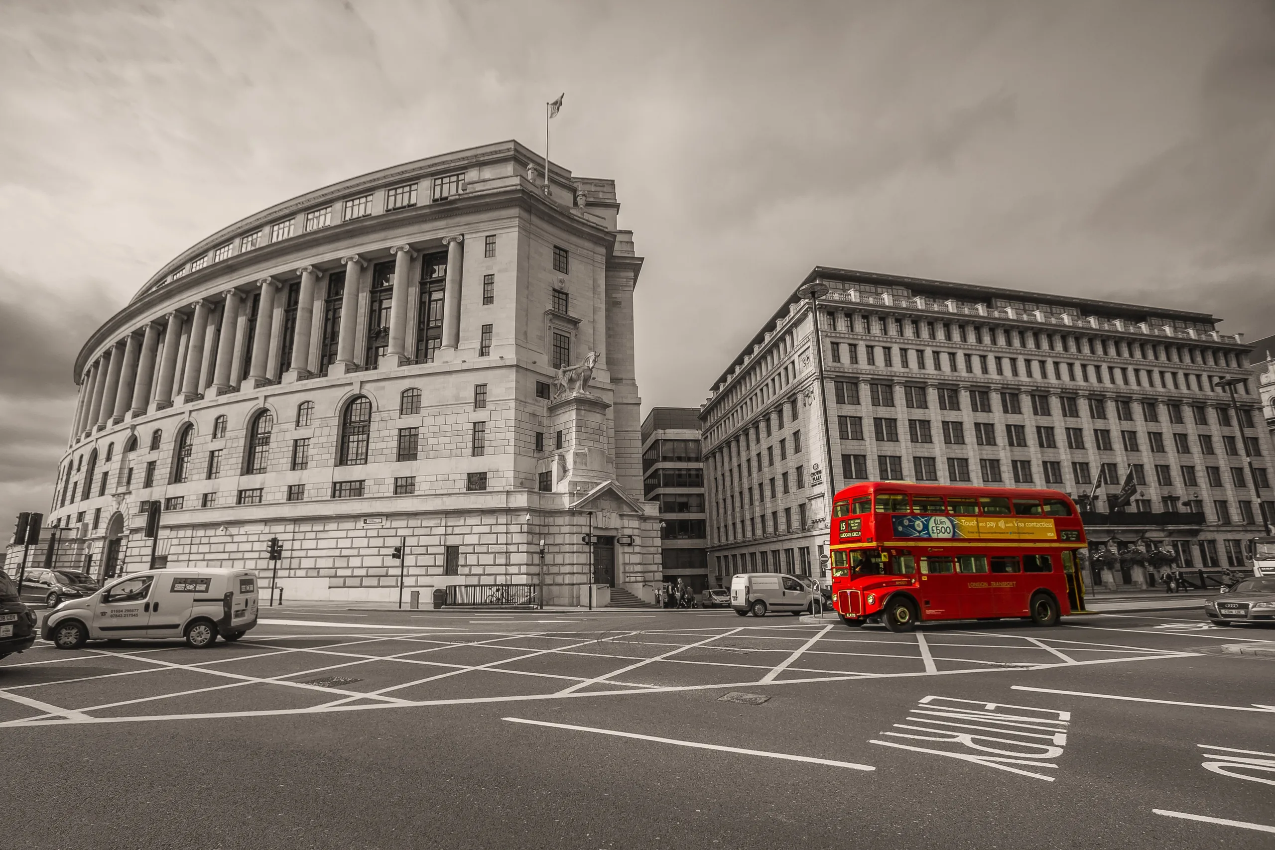 A red London bus passing the Portland-stone facades of the City of London
